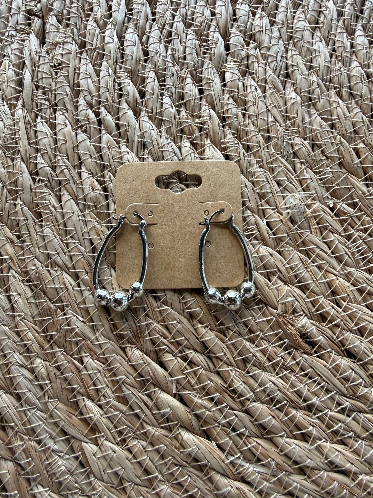 J1 silver earrings by Ivy's Gifts, featuring a sleek design with shimmering finish, elegantly displayed on a white background.