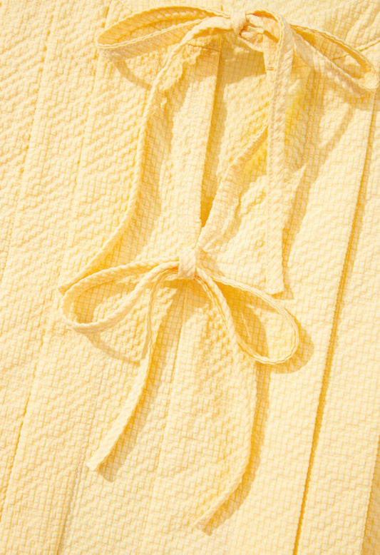 Yellow sleeveless blouse with trendy bow closure and pleats, stylish top from Ivy's Gifts & Boutique