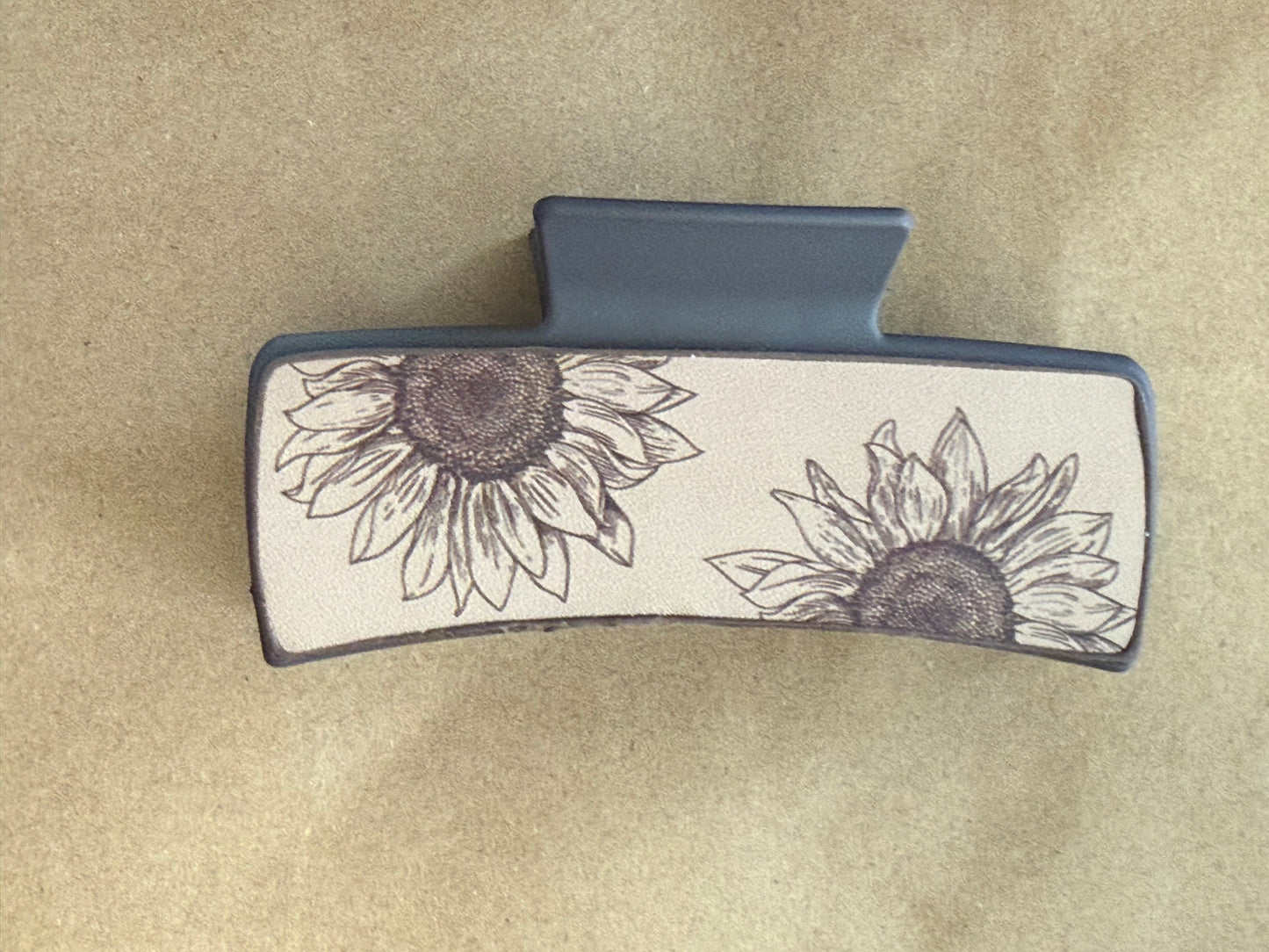A sunflower-shaped leatherette claw clip from Ivy's Gifts & Boutique, showing a bright yellow sunflower design with a sturdy clasp.
