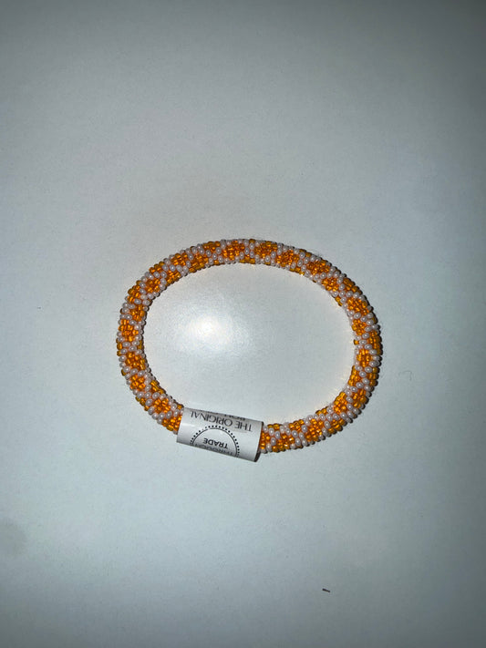 Rob Aid Through Trade roll-on bracelets by Ivy's Gifts & Boutique displayed on a wrist with colorful beads and metal accents.