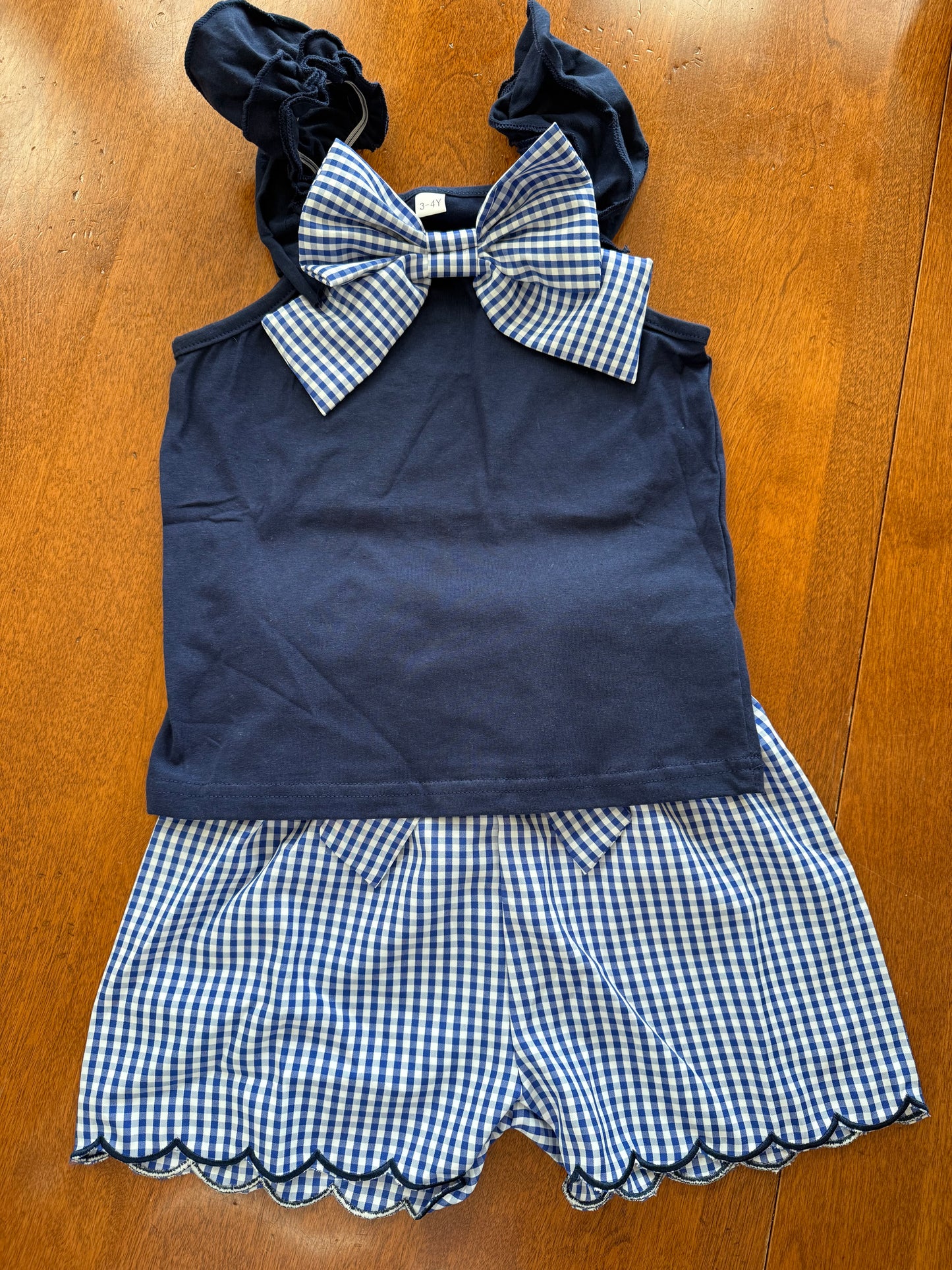Navy gingham bow detail short set by Ivy's Gifts & Boutique featuring scallop hem design on matching top and shorts.