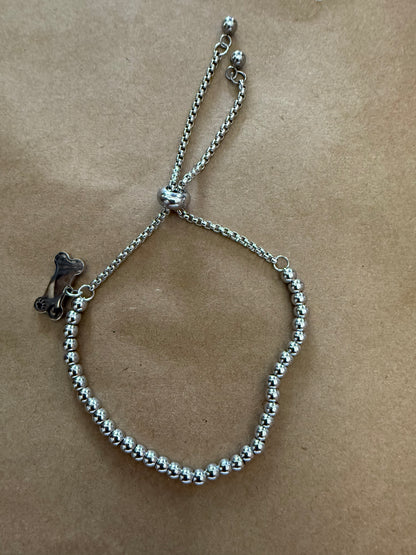 Silver dog bone charm bracelet with adjustable slide closure, featuring a stylish design from Ivy's Gifts & Boutique.