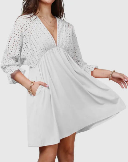 Cotton eyelet bodice dress with 3/4 length sleeves from Ivy's Gifts & Boutique, shown on a hanger with a floral background.