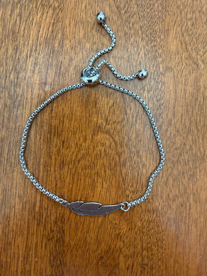 Silver feather design bracelet with slide adjustable latch from Ivy's Gifts & Boutique, featuring elegant feather charms on a sleek silver band.
