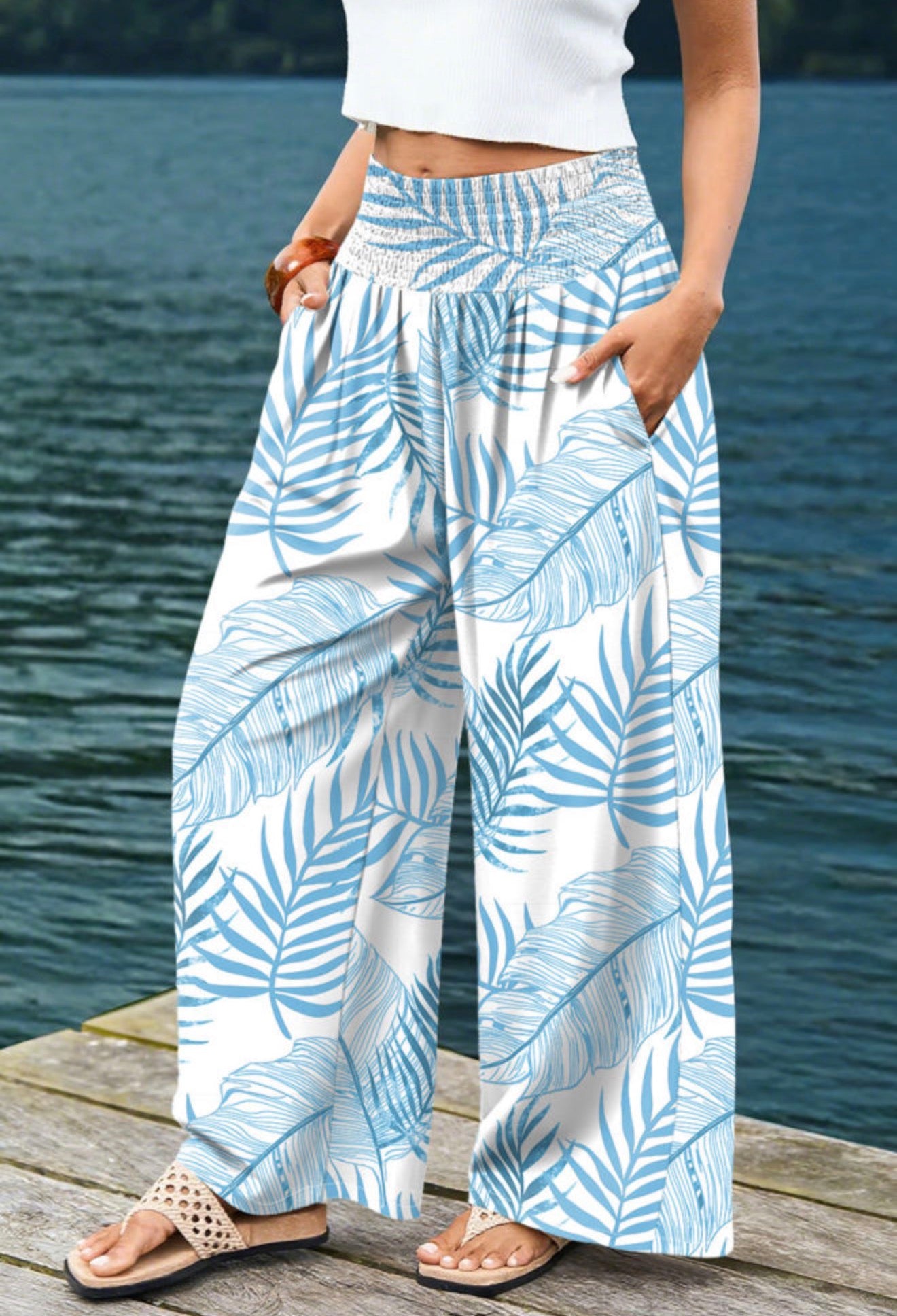 Wide-leg blue tropical leaf print pants by Ivy's Gifts & Boutique, featuring pockets and an elastic waistband.
