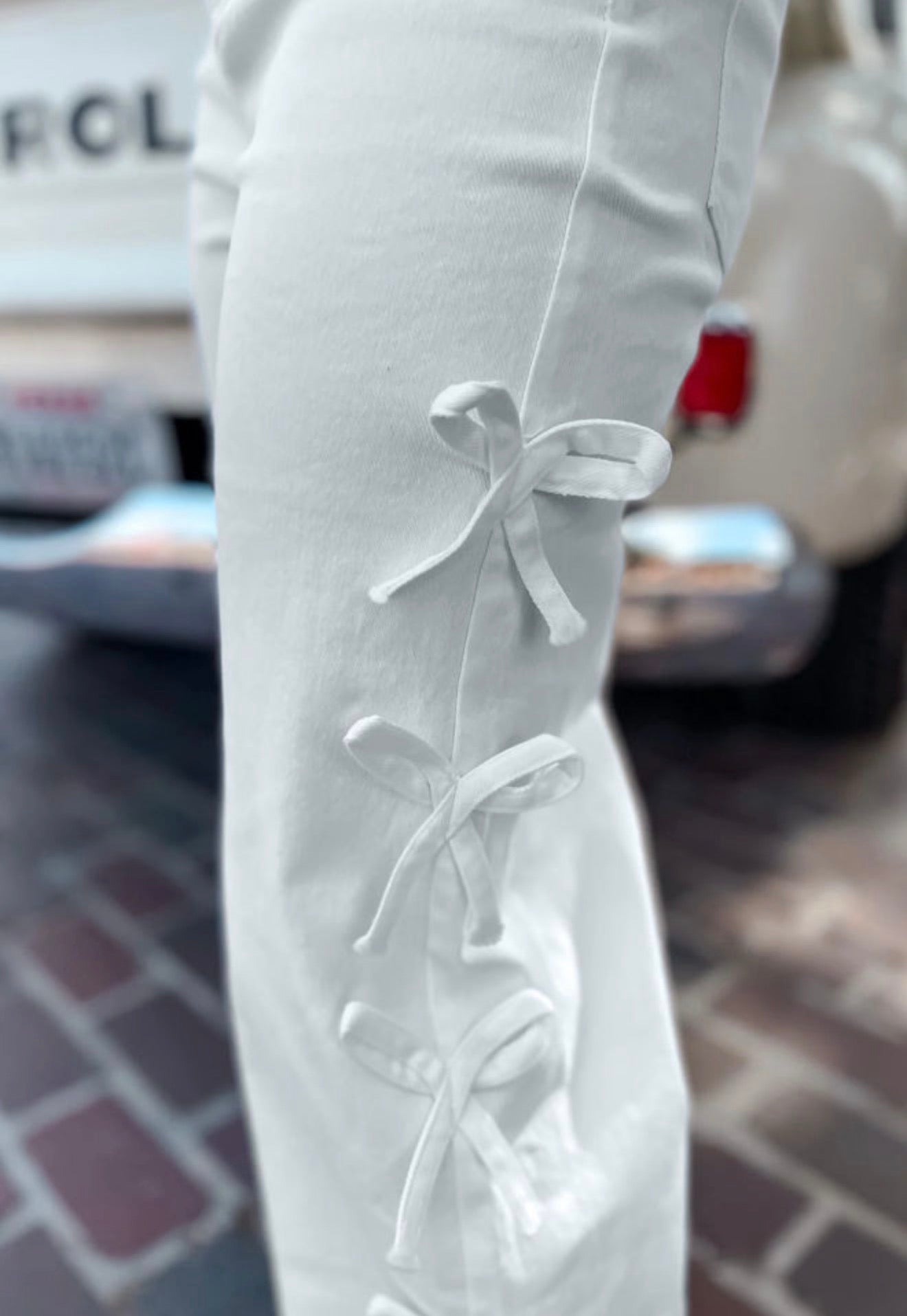 White jeans from Ivy's Gifts & Boutique with cute side seam bow details and classic five-pocket design.