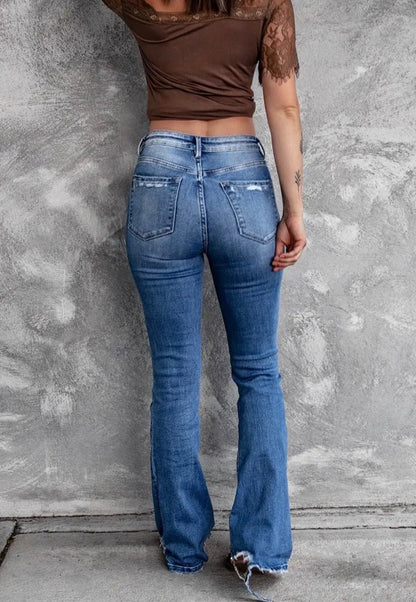 Distressed blue jeans with flare legs and frayed hems from Ivy's Gifts & Boutique, shown on a model.