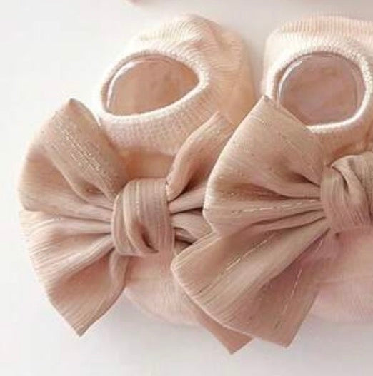 Baby's ivory BT1 infant gripper sock with adorable toe bow embellishment, soft and stretchy for comfortable wear.