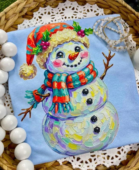 Light blue T-shirt featuring a snowman with scarf design from Ivy's Gifts & Boutique.