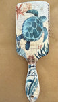 Sea turtle-shaped hair brush by Ivy's Gifts & Boutique with a wooden handle and detailed turtle design for gentle detangling