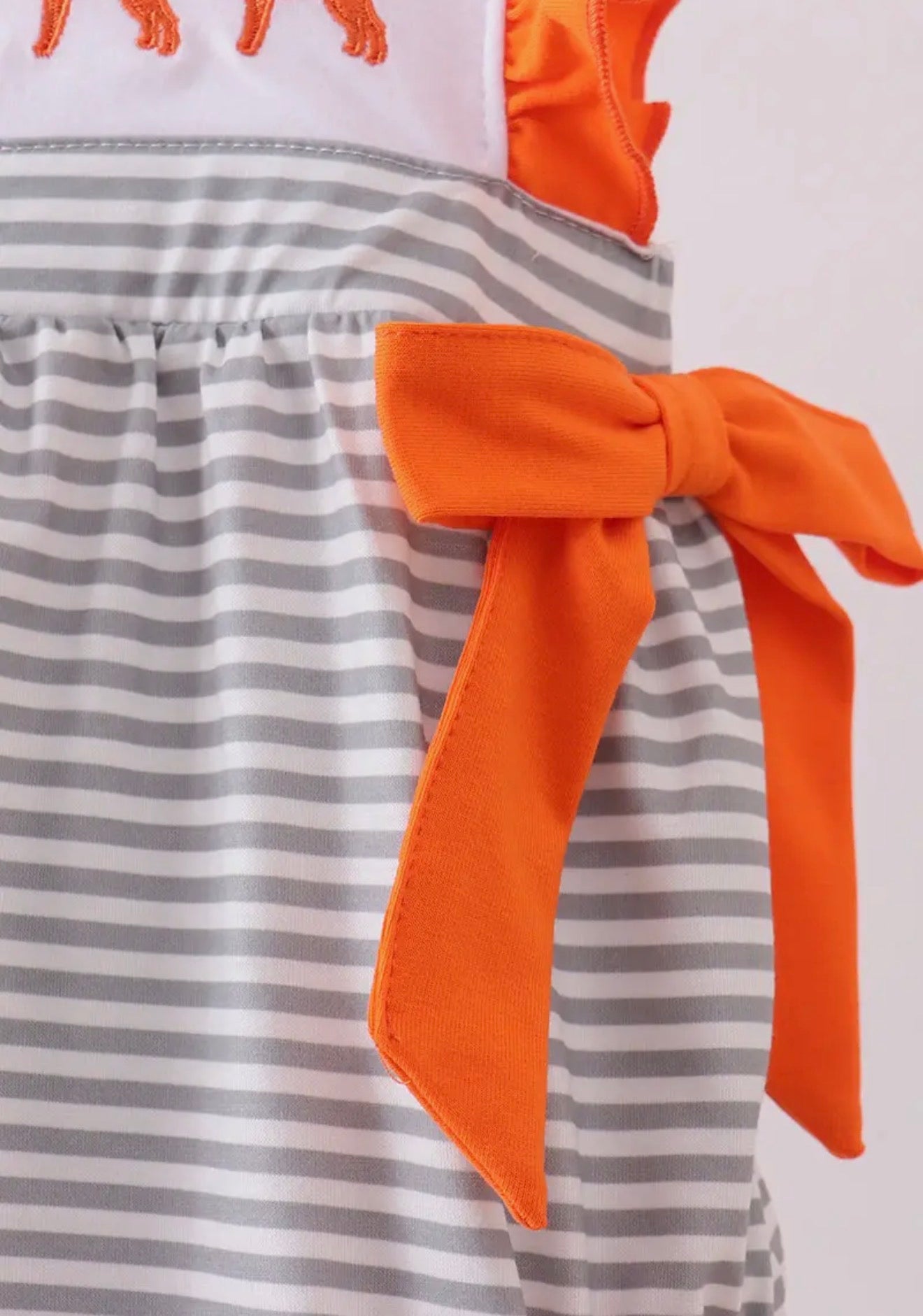 Baby girl TN5 orange and white romper by Ivy's Gifts & Boutique with gray stripe embroidery and side bows, on a white background.