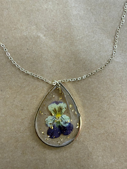 Dried flower pendant necklace featuring a delicate floral design on a silver chain by Ivy's Gifts & Boutique.