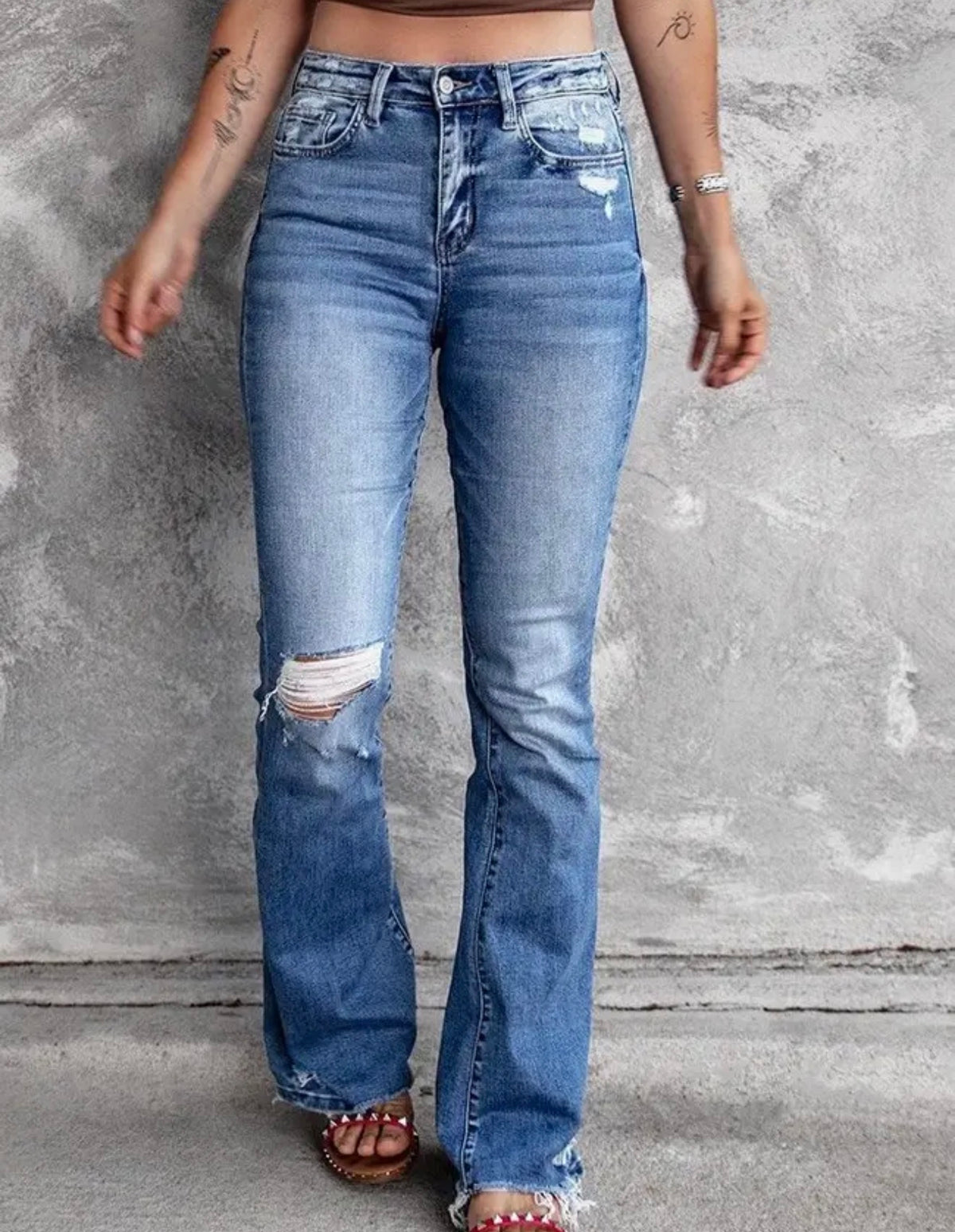 Distressed blue jeans with flare leg and frayed hem from Ivy's Gifts & Boutique, showcasing trendy casual denim style.