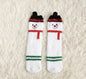 Ivy's Gifts & Boutique holiday socks with pom pom accents, featuring festive patterns and cozy knit fabric.