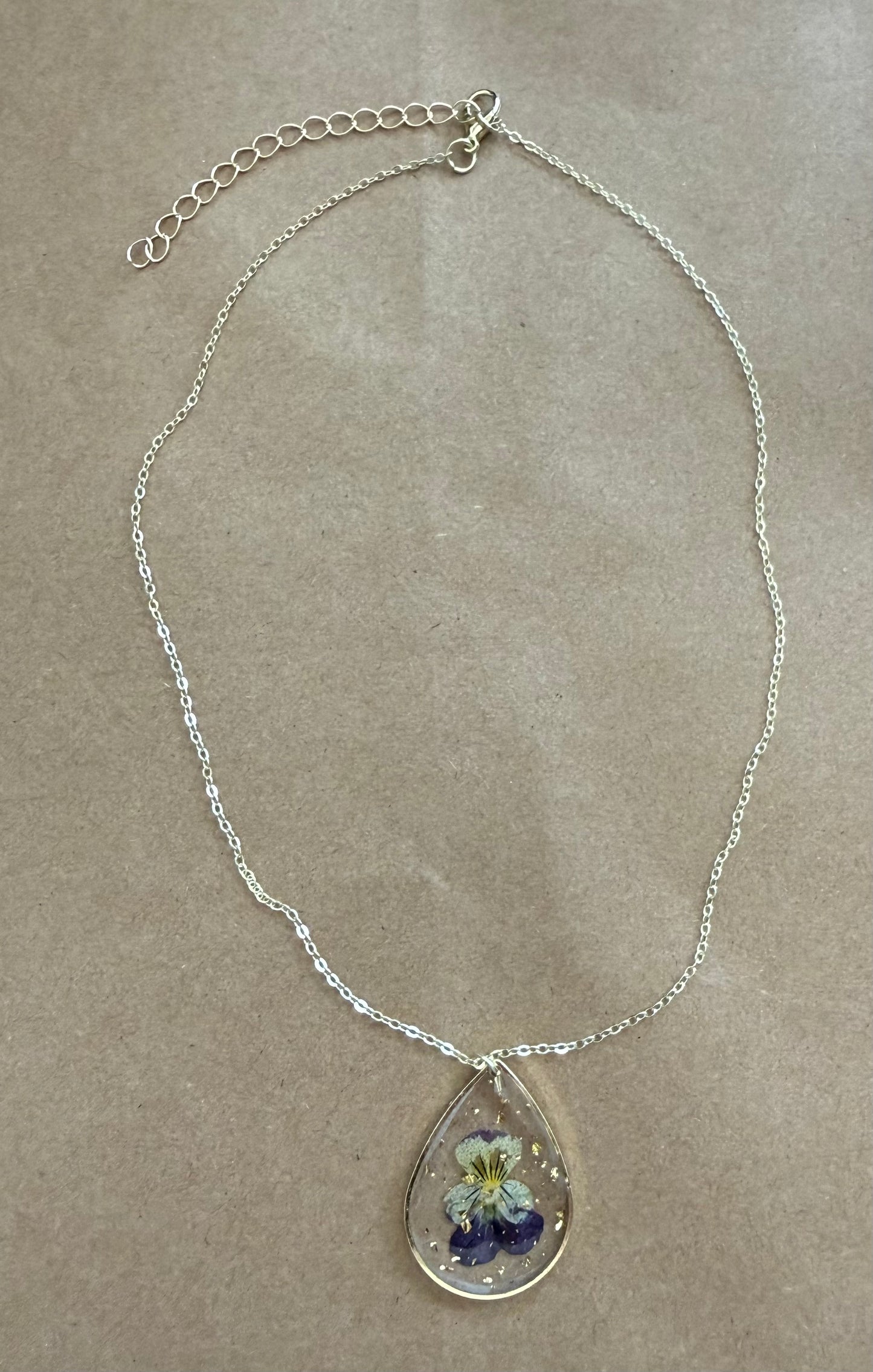 Dried flower pendant necklace with a gold chain, featuring a clear glass globe with preserved flowers, from Ivy's Gifts & Boutique.