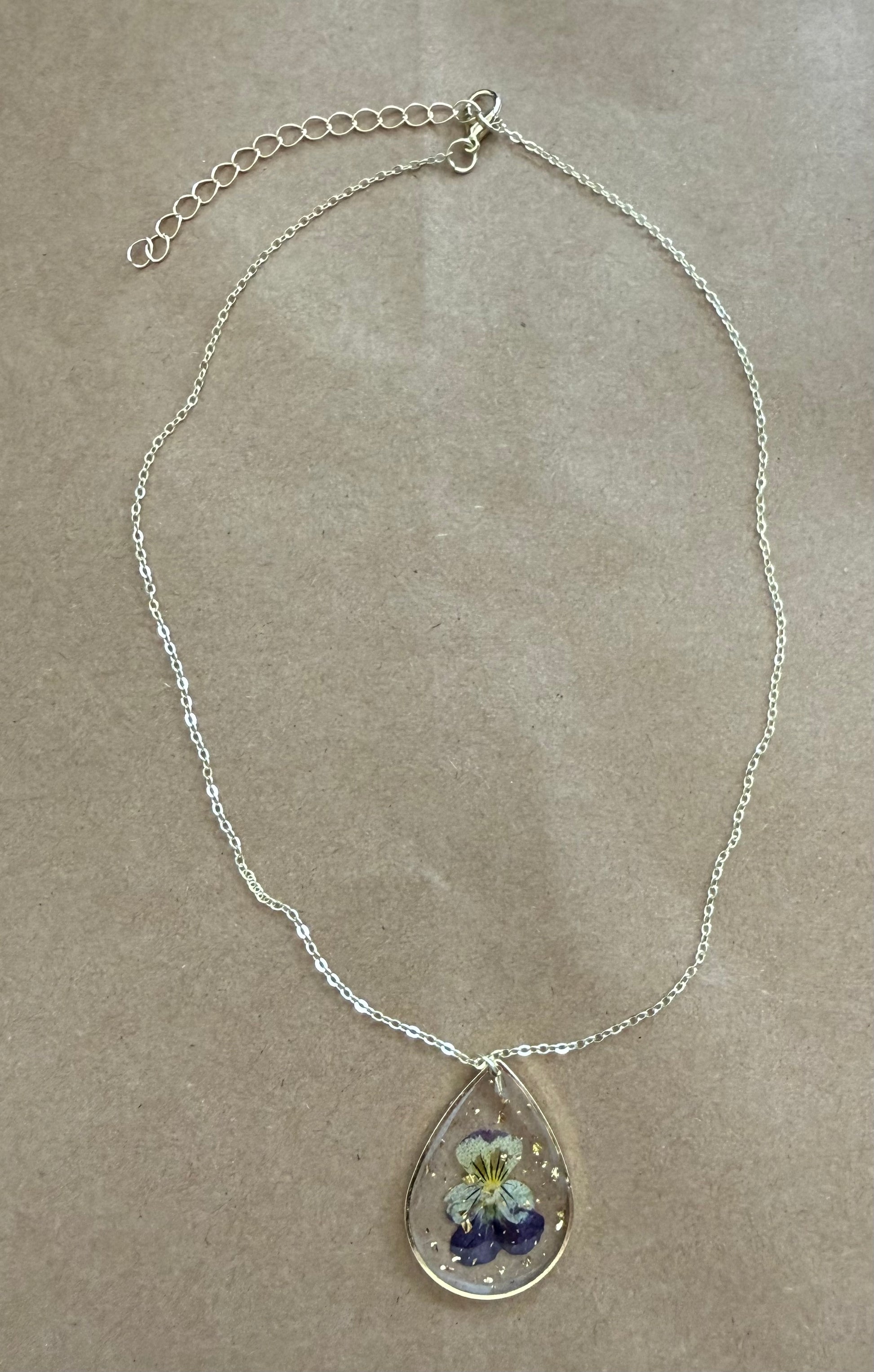 Dried flower pendant necklace with a gold chain, featuring a clear glass globe with preserved flowers, from Ivy's Gifts & Boutique.