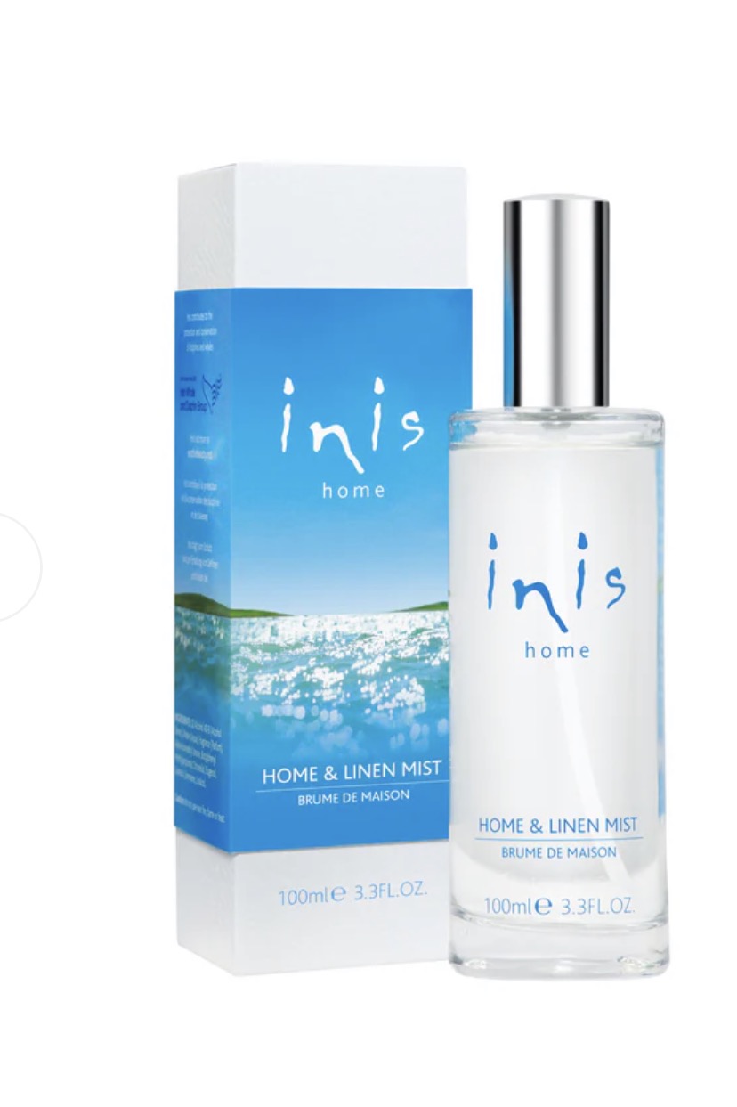 Inis bath and body products set with bottles of lotion and body wash, displayed on a white surface with greenery.