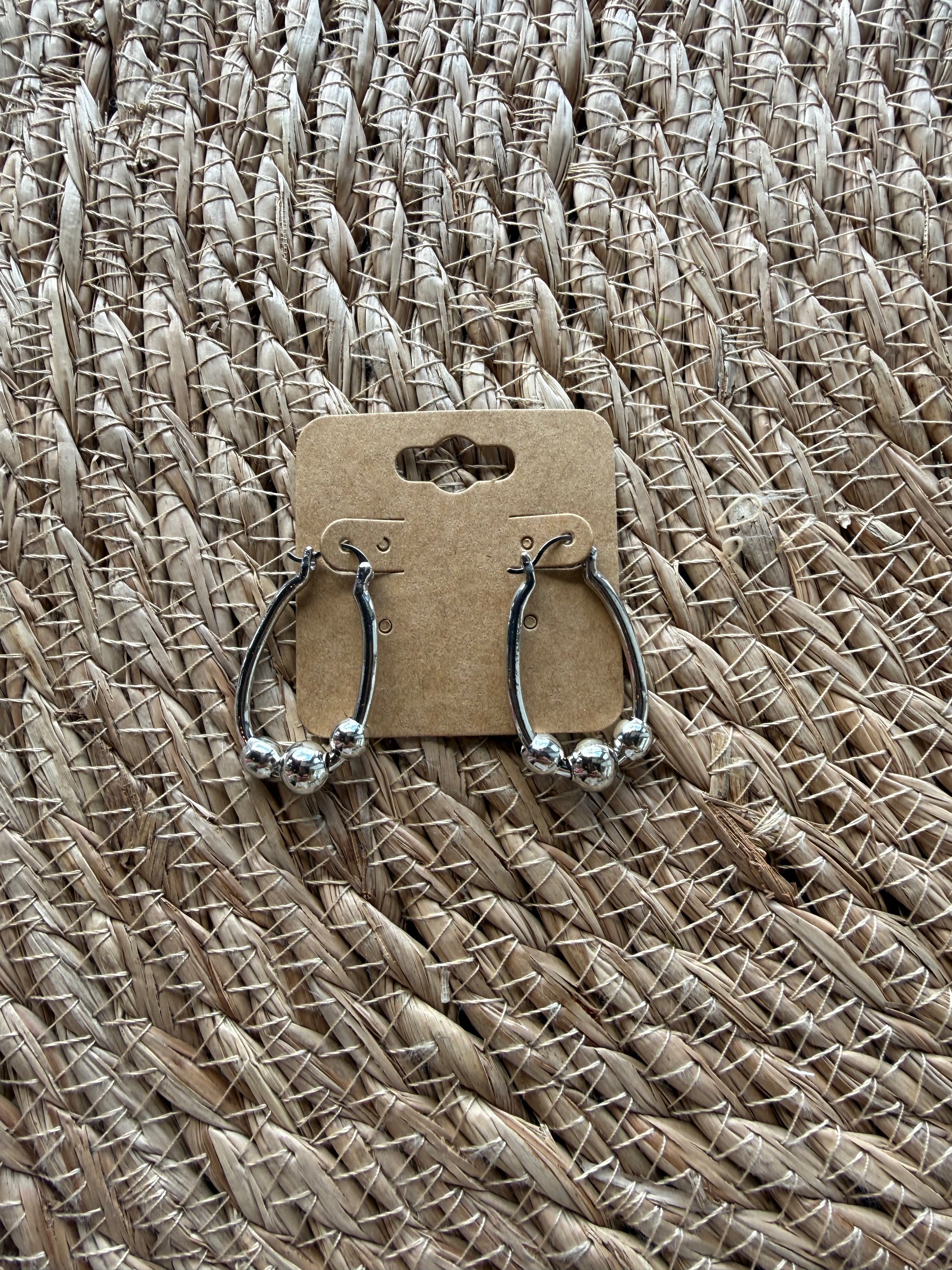 J1 silver earrings by Ivy's Gifts, featuring a sleek design with shimmering finish, elegantly displayed on a white background.